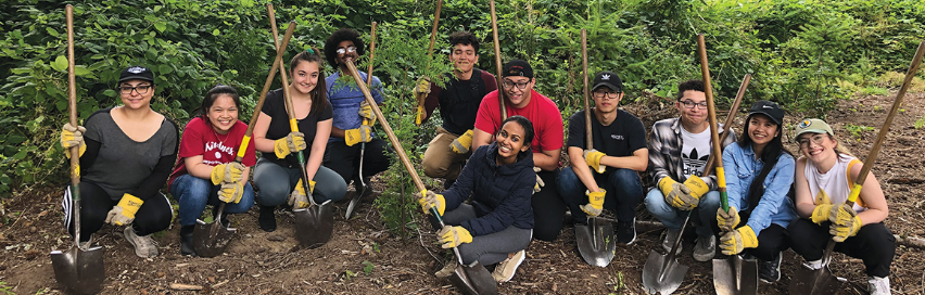 Group of people with shovels and other gardening tools.